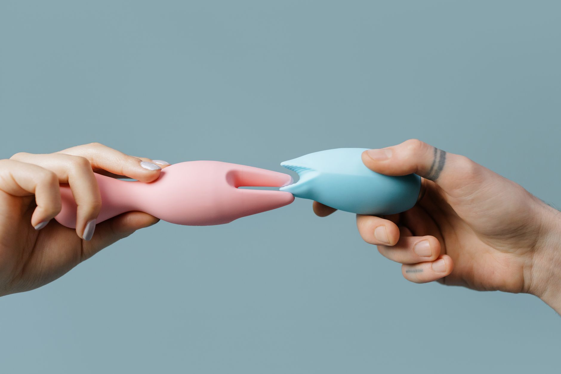 Casal jovem em pé junto, segurando um vibrador azul, simbolizando intimidade moderna