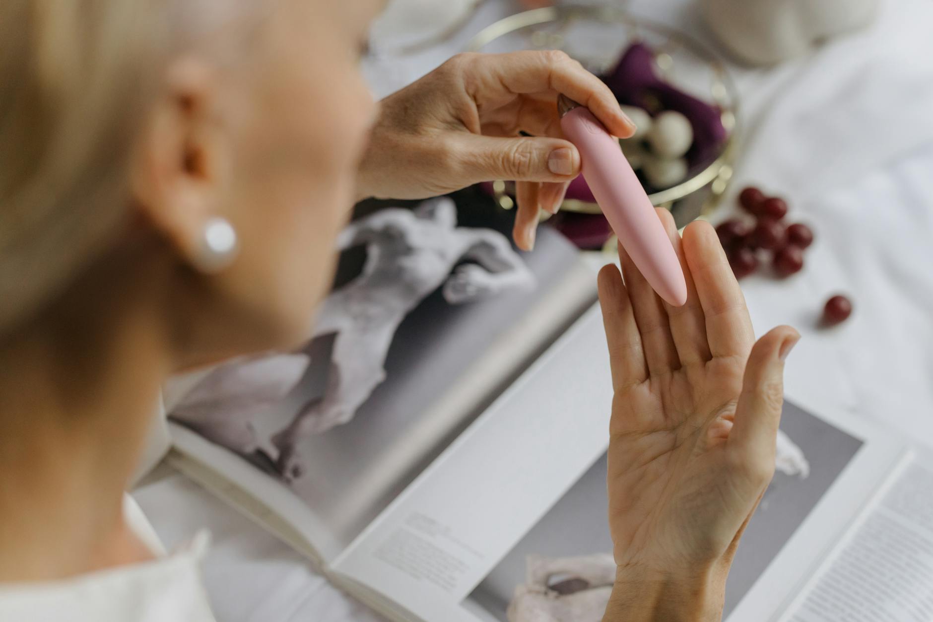 Mão segurando um vibrador de silicone azul contra fundo roxo pastel, celebrando amor-próprio e sexualidade