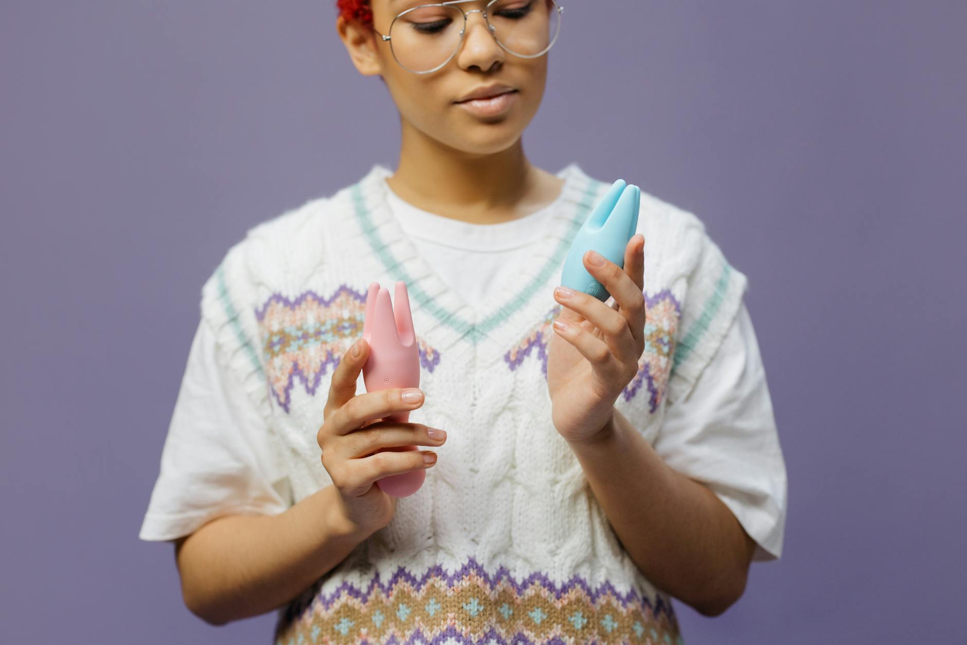Mulher com óculos segurando vibrador de silicone em tom contemplativo