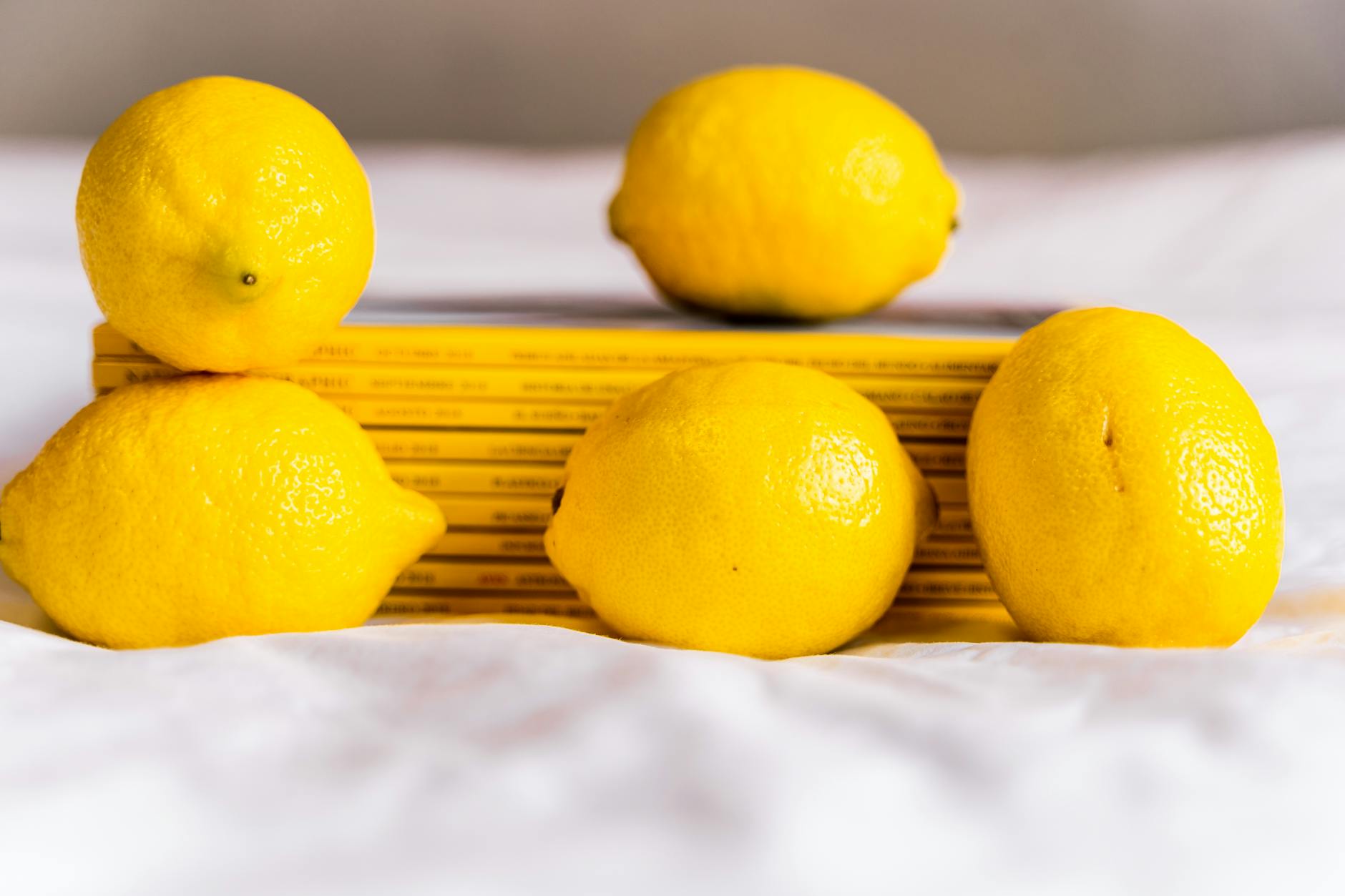 Yellow silicone lemon vibrator surrounded by fresh citrus on a bright background